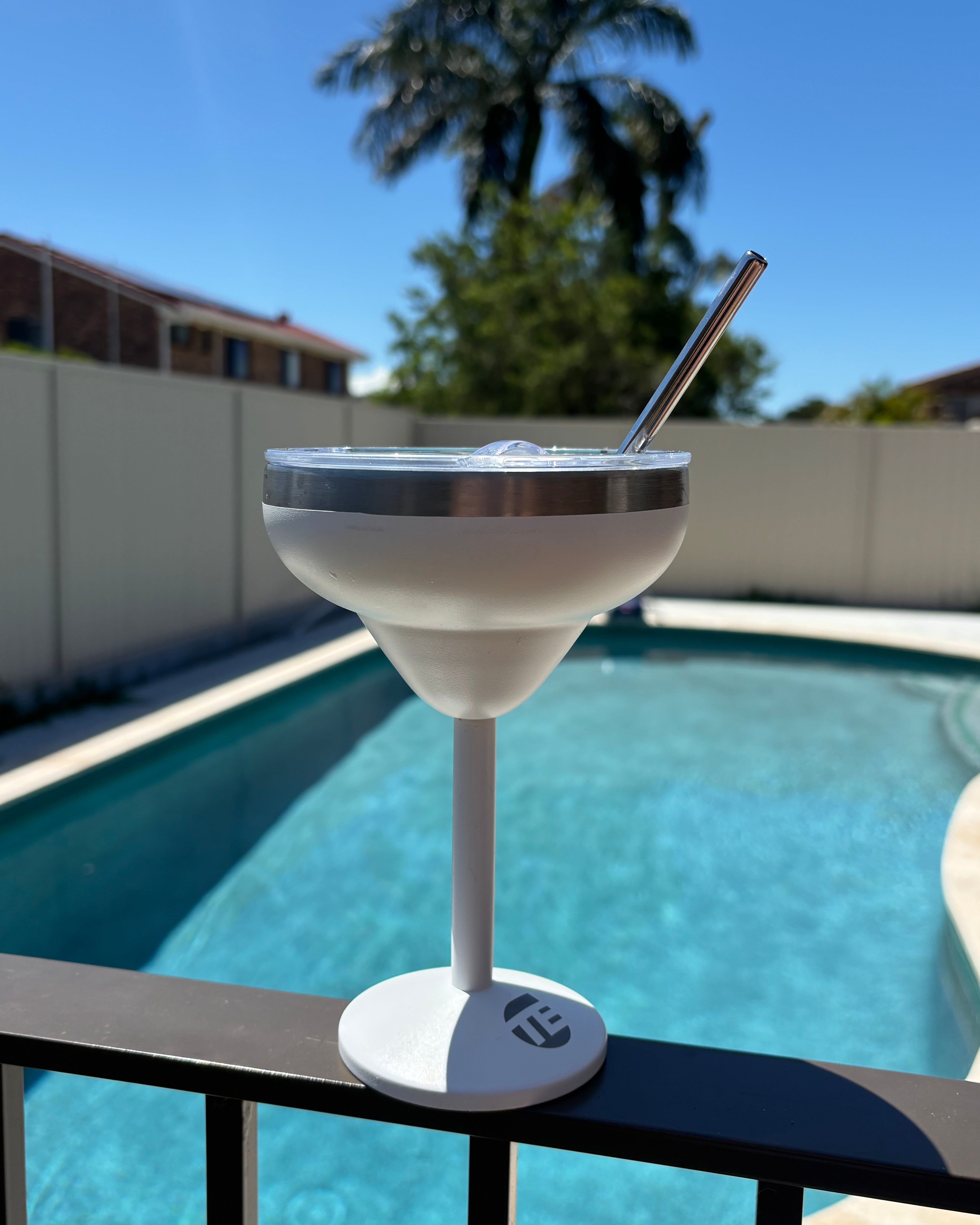insulated coffee cup with straw near a pool