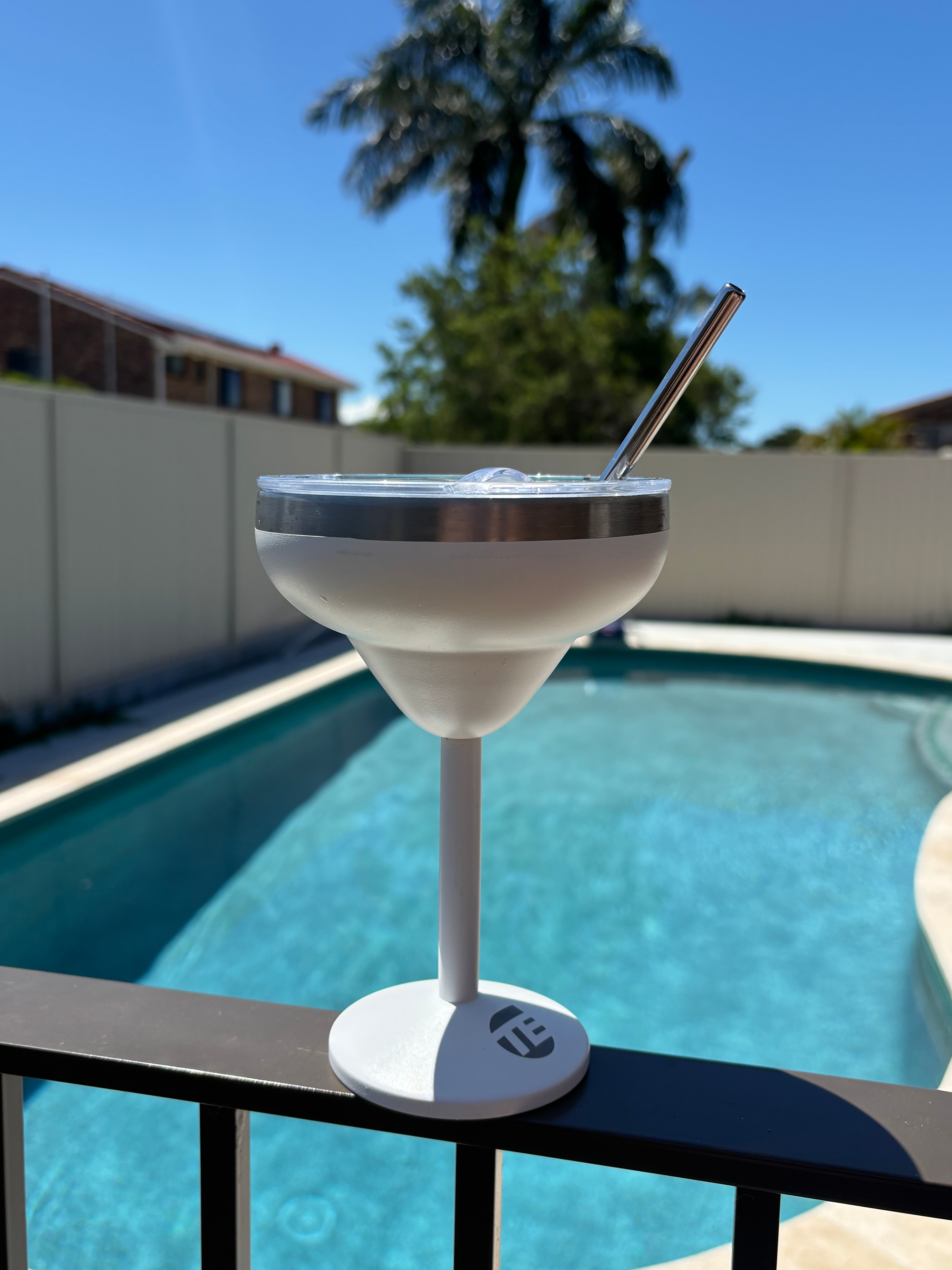 insulated coffee cup with straw near a pool