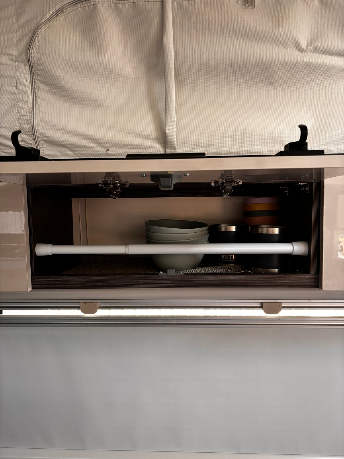 rod tension bar holding in plates and cups in a caravan cupboard