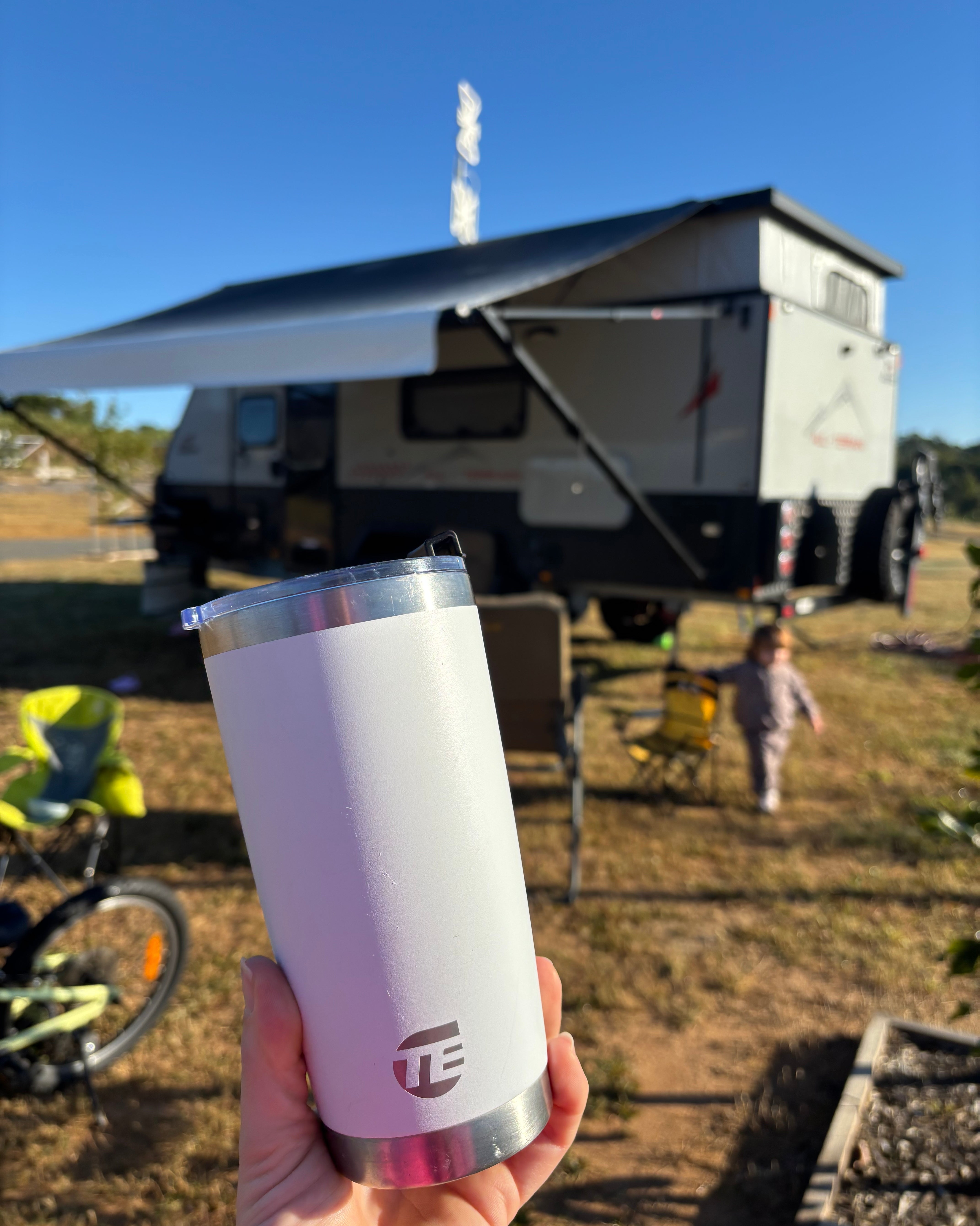 white insulated coffee cup with caravan in the background