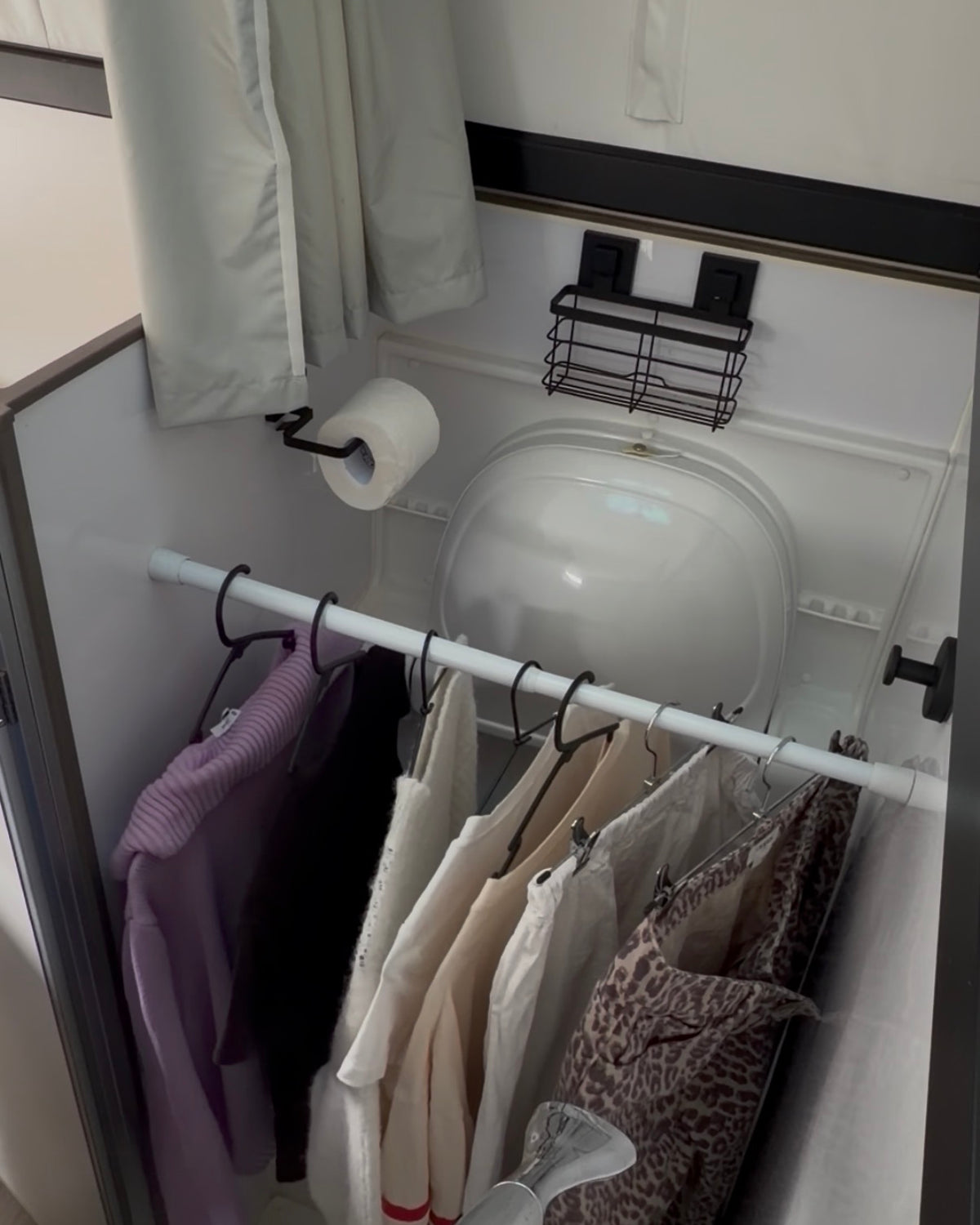 a tension rod in a caravan bathroom with clothes hanging on it to dry.