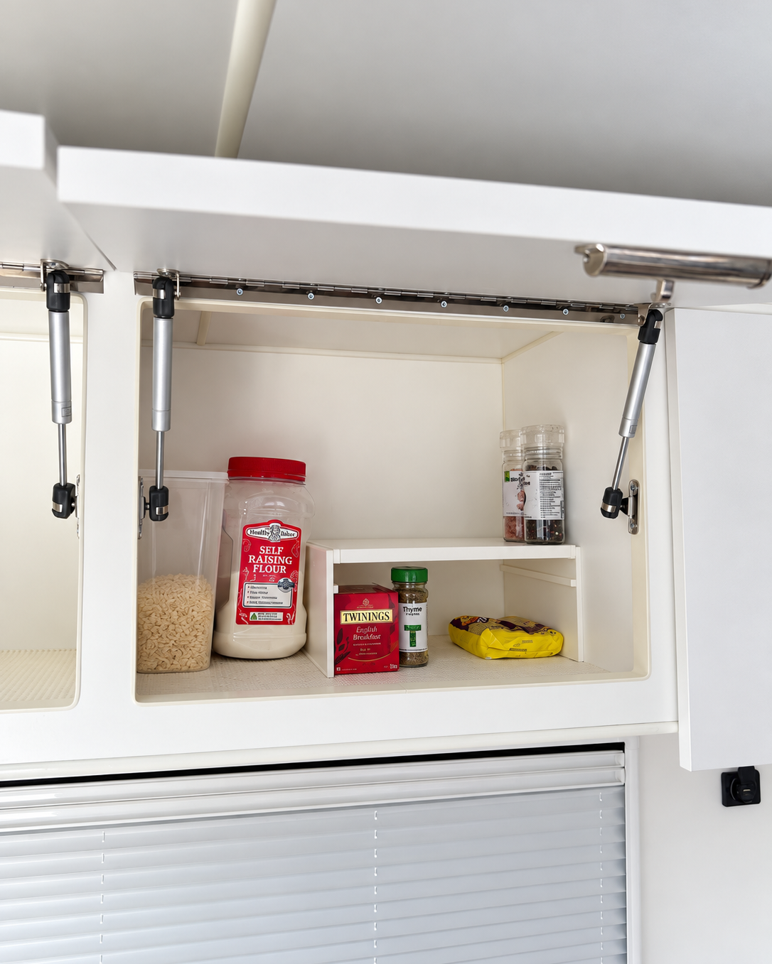 white extendable plastic shelf with items underneath to showcase room in a caravan cupboard