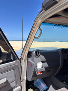 70 Series Land Cruiser on the beach with a door open and cup holder
