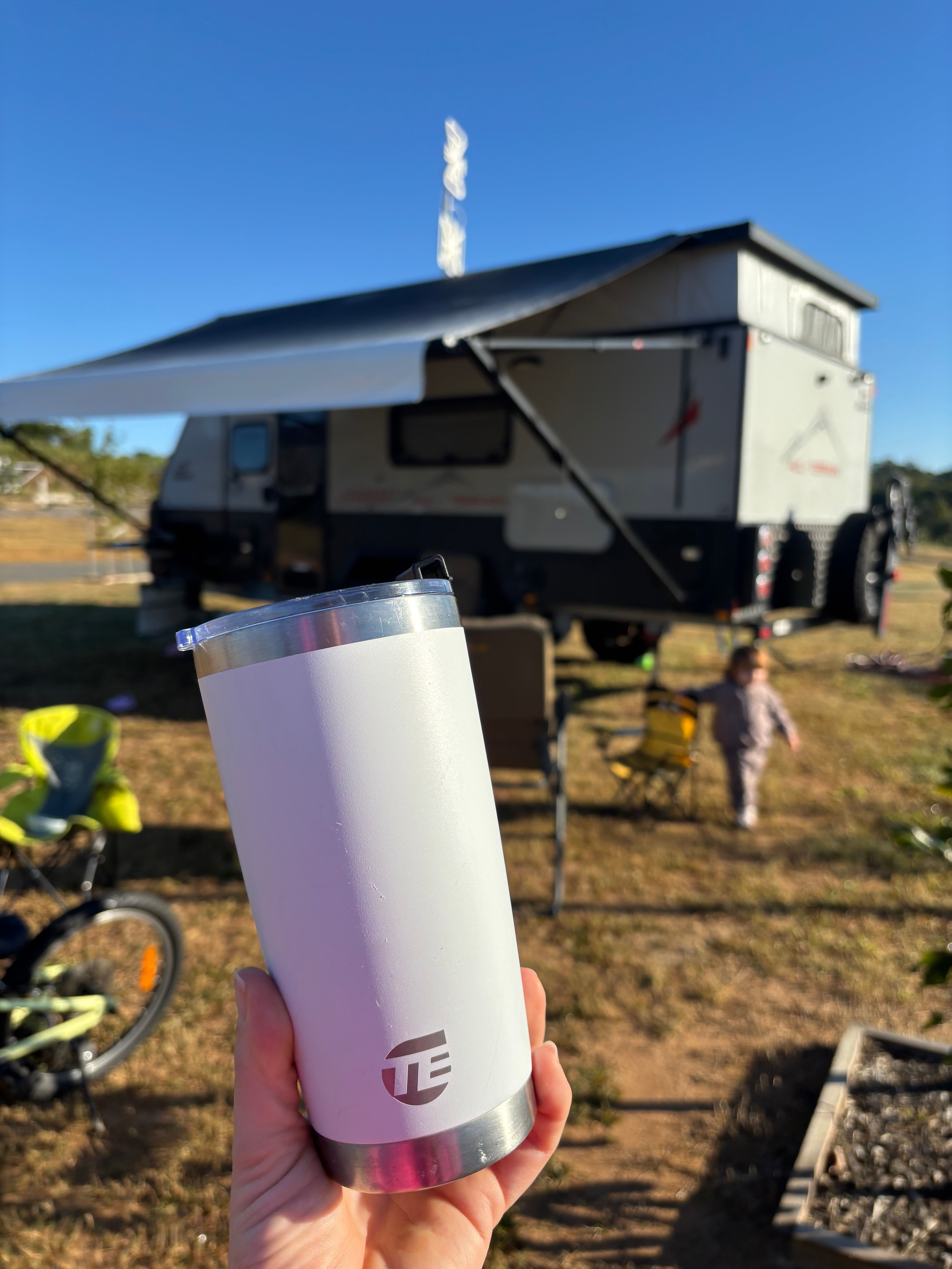 white insulated coffee cup with caravan in the background