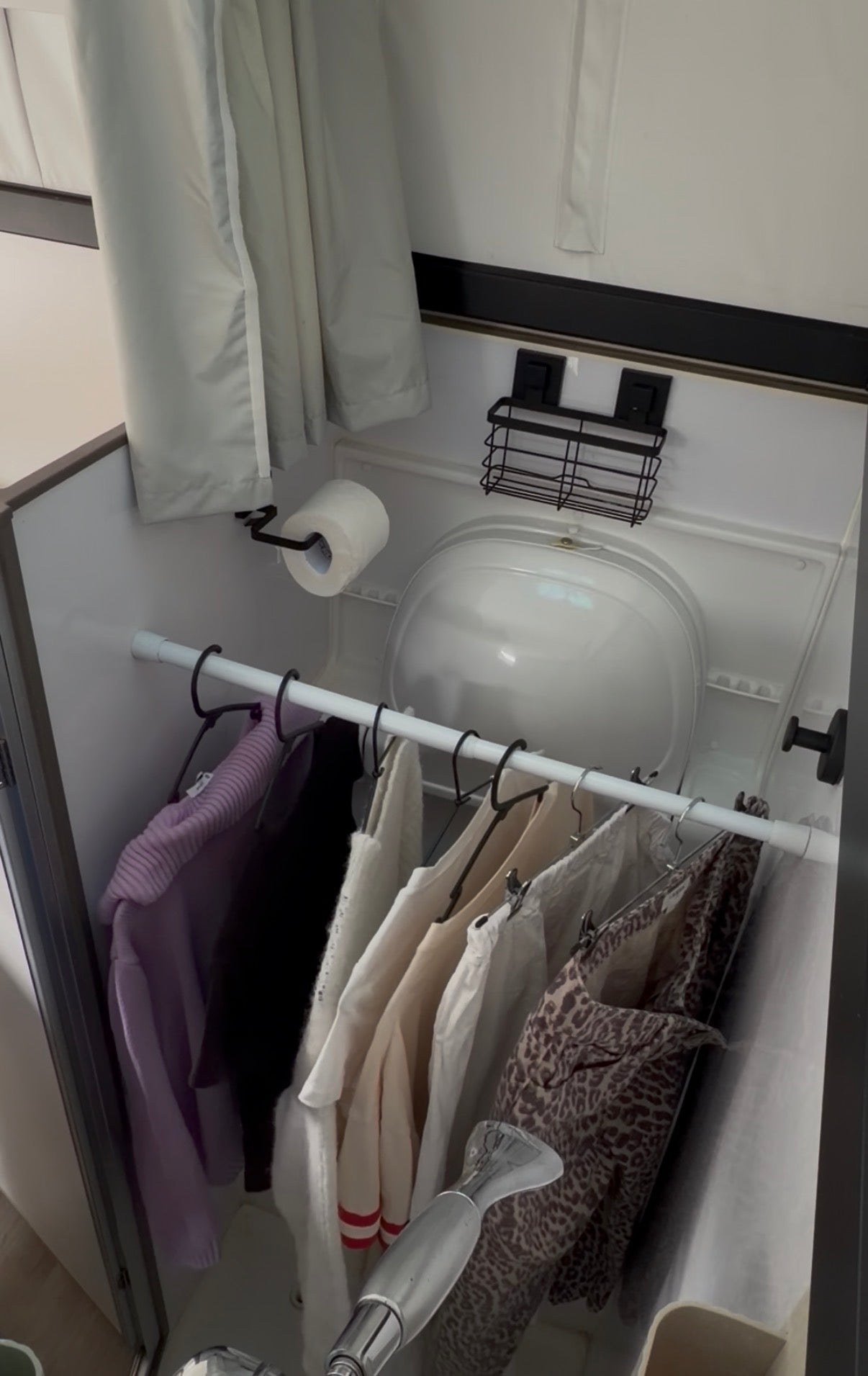 a tension rod in a caravan bathroom with clothes hanging on it to dry.